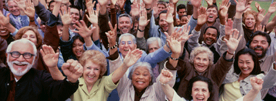 Multi-racial audience smiling and waving at the camera.